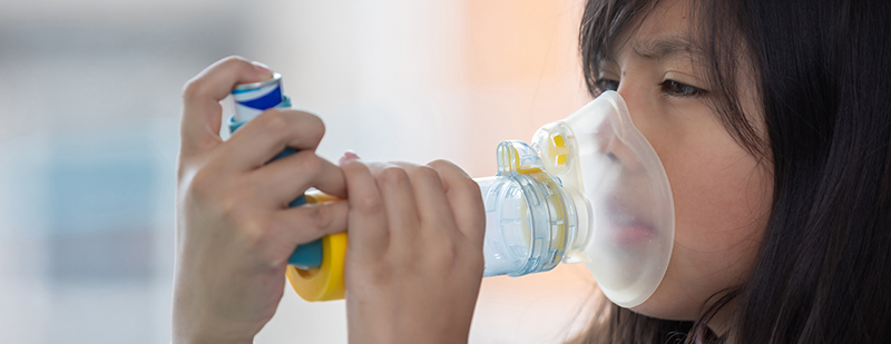 Girl using inhaler with spacer