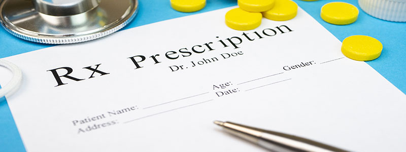 Empty prescription pad with pills scattered on top