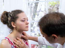 Doctor examining patient's thyroid