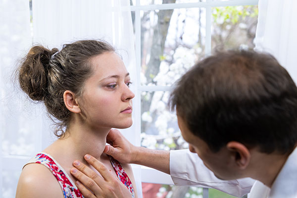 Doctor examining patient's thyroid