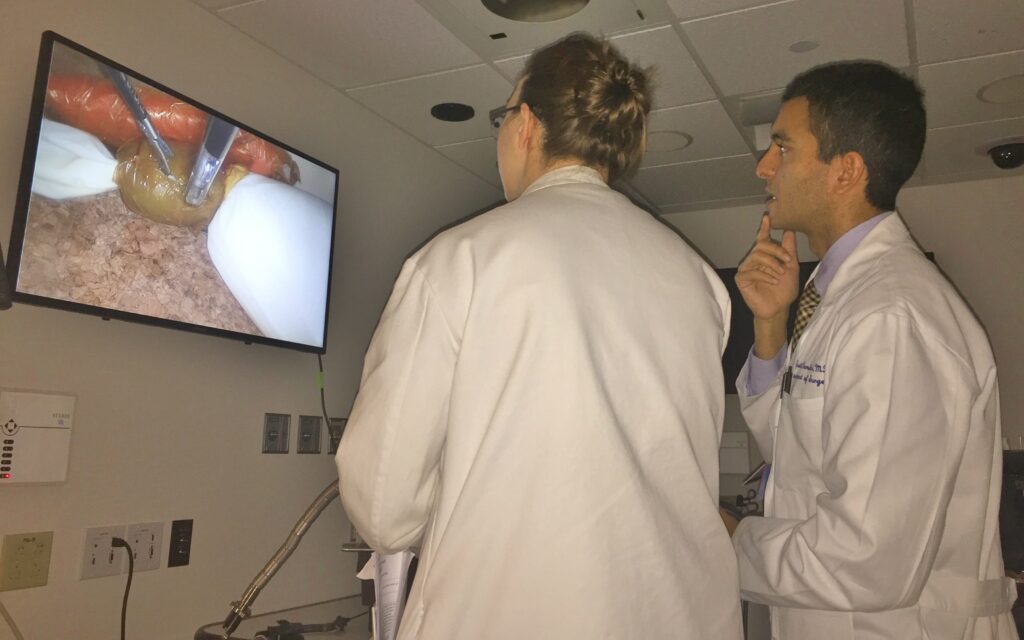 Fellows study an on-screen image.