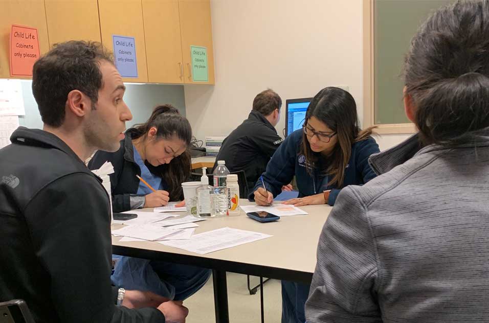 Fellows meet around a table, filling out paperwork